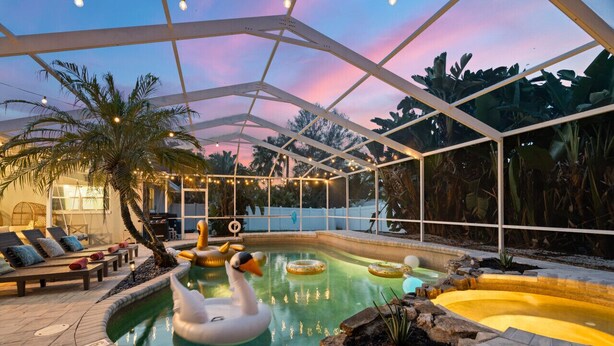 A pool area with a swan float, palm trees, and a covered seating area.