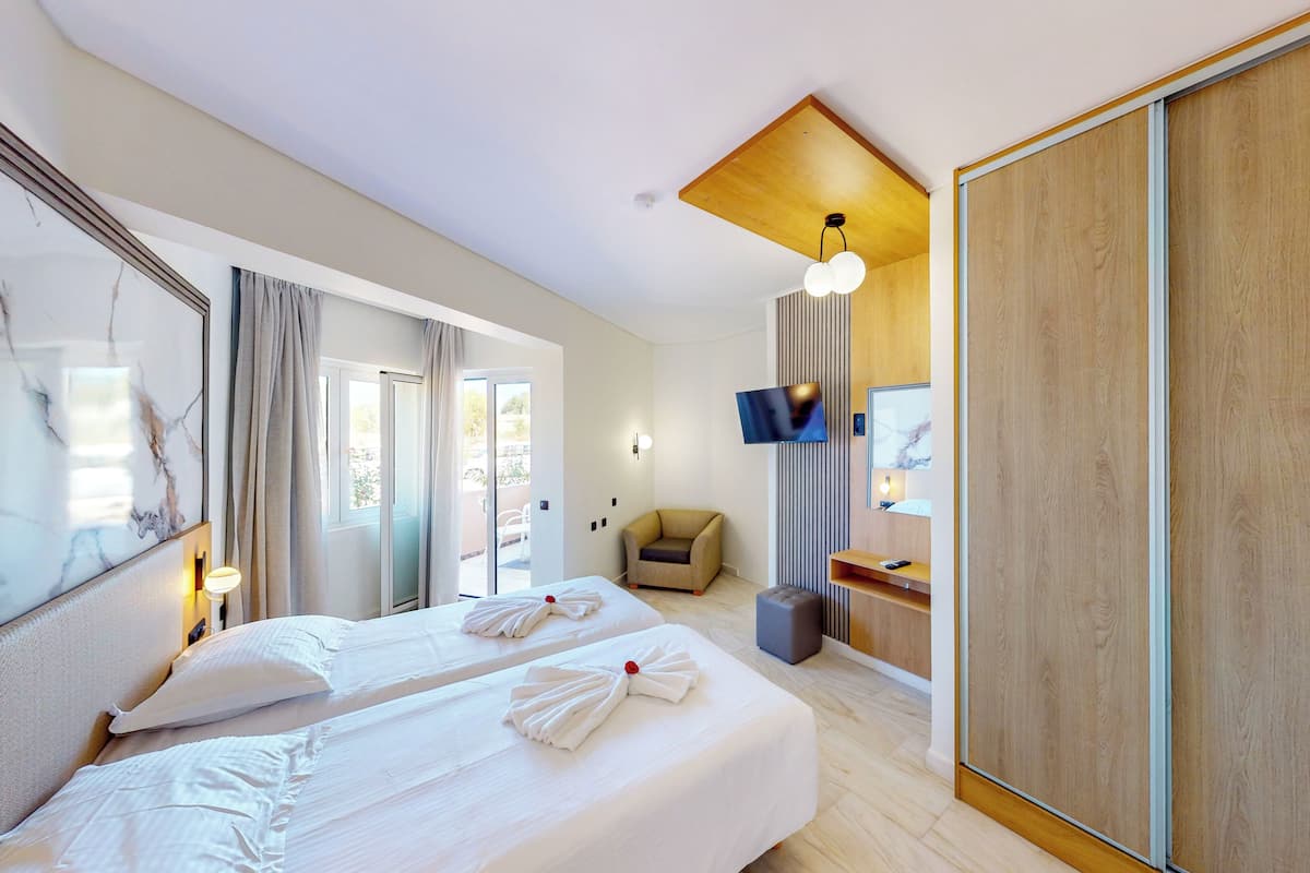 A hotel room with two beds, a large mirror, a TV, and a sliding wooden door.