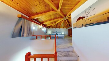 Ένα υπνοδωμάτιο με ξύλινη οροφή, ένα κρεβάτι, ένα κομοδίνο και ένα φωτιστικό τοποθετημένο στον τοίχο.