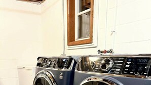 Eine Waschmaschine und ein Trockner in einem Hauswirtschaftsraum mit einem Fenster darüber.