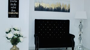 A black upholstered sofa with a tufted backrest and decorative studs, positioned against a white wall. - Luxury studio near IAH (Humble)