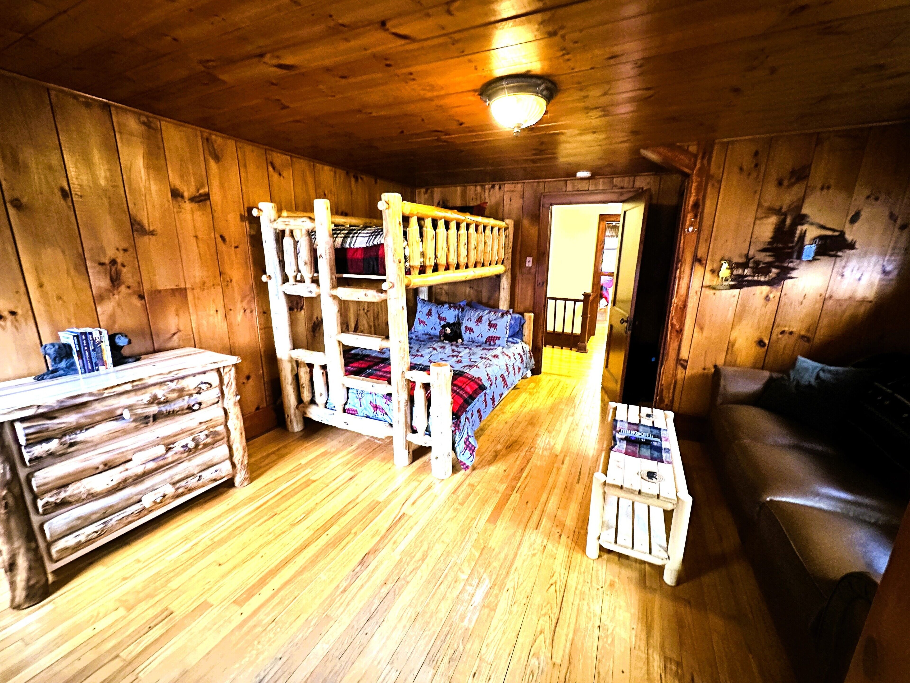 Interior rústico de una cabaña con una litera, un aparador de madera y una mesita.