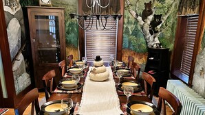 Comedor con una larga mesa dispuesta para una comida, rodeada de sillas.
