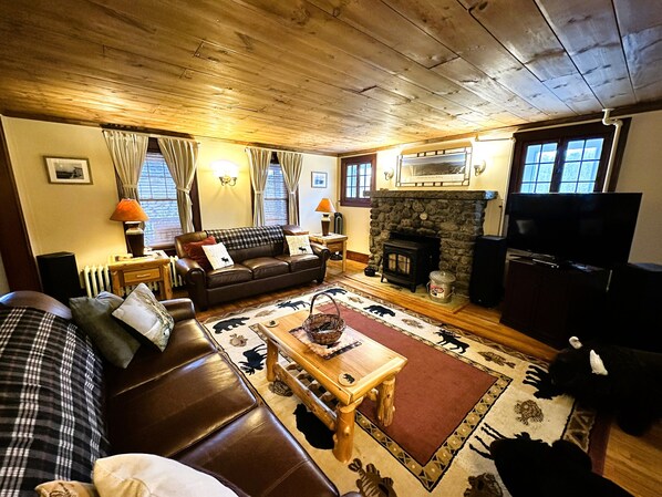 A cozy living room with a fireplace, a sofa, a television, and a patterned rug.
