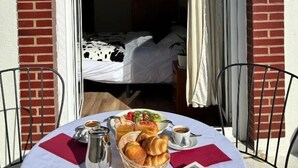 A hotel room with a bed, a dining table with breakfast, and a view through an open door. - Hotel Restaurante Bicis & Vacas (La Pola de Gordón)