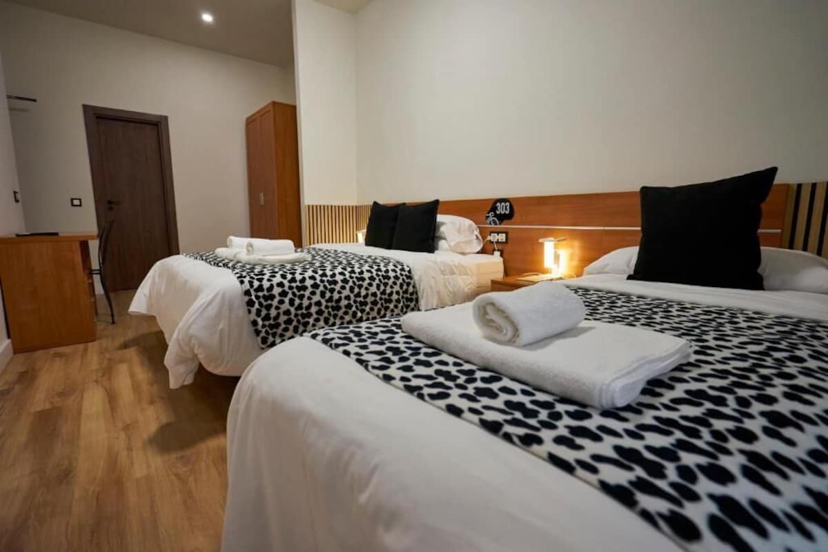 Una habitación de hotel con dos camas, un cabecero de madera, un escritorio y una puerta.