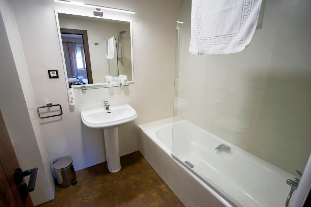 Un bagno con un lavandino bianco, una cabina doccia in vetro e una vasca da bagno bianca.