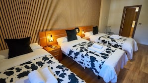 A hotel room with three beds, each with a cow print bedspread, a wooden headboard, and bedside lamps. - Hotel Restaurante Bicis & Vacas (La Pola de Gordón)