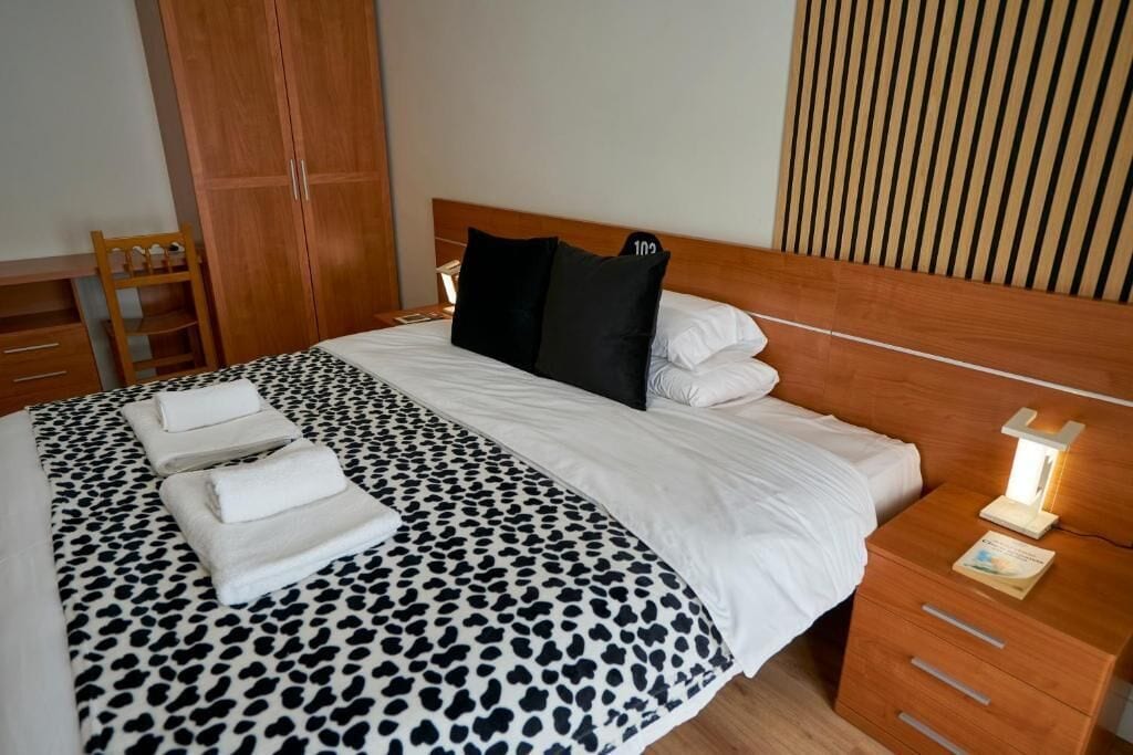 Ein Hotelzimmer mit einem Bett, einem Nachttisch mit Lampe, einem Holzschrank und einem Schreibtisch mit Stuhl.
