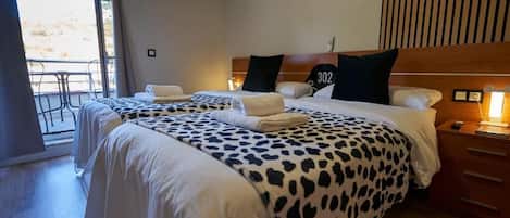 A hotel room with two beds, a balcony, and a wooden headboard.