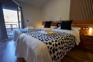 Habitación de hotel con dos camas, un balcón y un cabecero de madera.