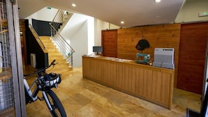 A reception desk with a bicycle parked nearby, a staircase, and a wooden wall. - Hotel Restaurante Bicis & Vacas (La Pola de Gordón)