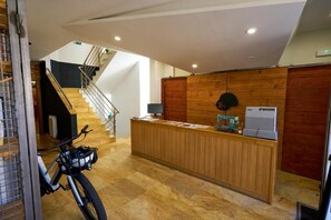 Una recepción con una bicicleta cerca, una escalera y una pared de madera.