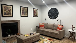 A living room with a sofa, ottoman, fireplace, and artwork on the wall. - Updated home strategically close to everywhere you want in El Paso and Cd Juárez (El Paso)