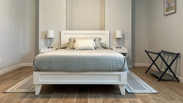 A bedroom with a bed, two bedside tables, a nightstand, a black folding chair, and a rug. - Updated home strategically close to everywhere you want in El Paso and Cd Juárez (El Paso)