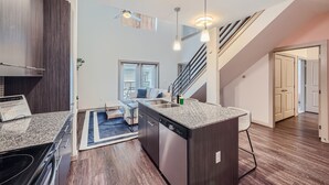 A modern kitchen with granite countertops, stainless steel appliances, and a built-in dishwasher. - Roomy 2B Loft Getaway | Sleeps 5 | Pool, Gym, Pkg, Pet Wash (Leander)