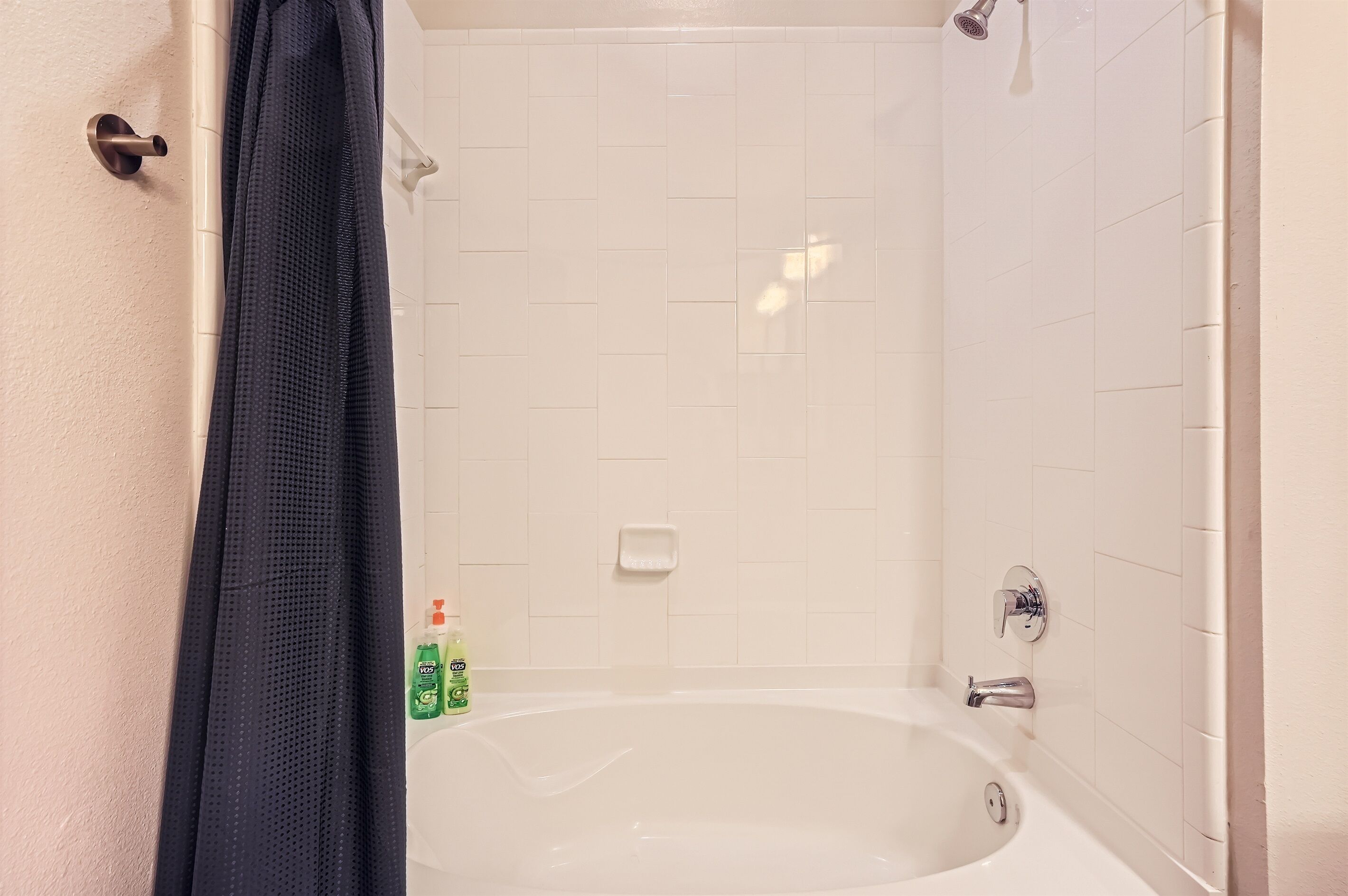Ein Badezimmer mit einer Badewanne, einer Duschvorhang und zwei Shampoo-Flaschen.