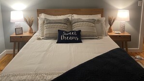 A neatly made bed with a black pillow labeled "Sweet Dreams" and two bedside lamps. -  Cozy A-frame cabin just a short walk to town. (Ogunquit)
