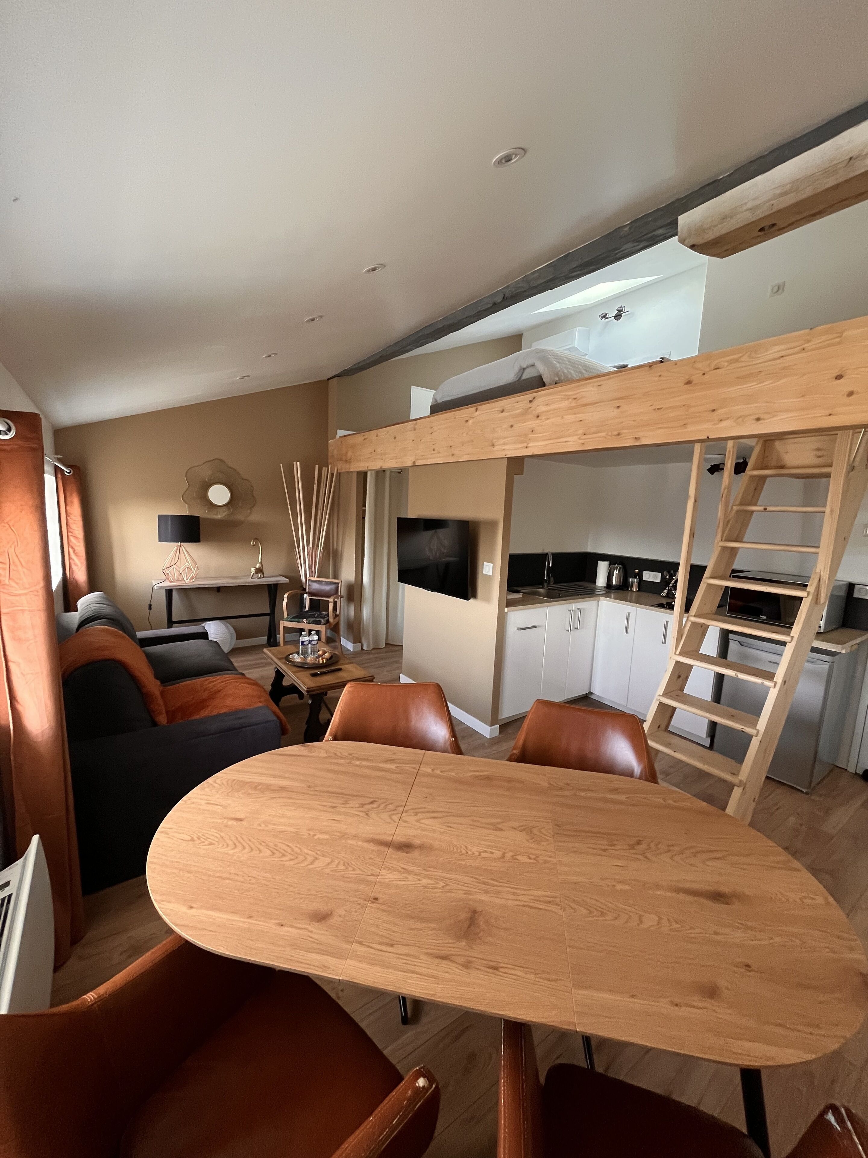 A compact living space with a bunk bed, a dining area, and a kitchenette.