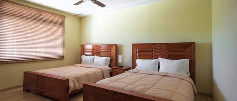 A bedroom with two wooden beds, a ceiling fan, and a window with blinds.