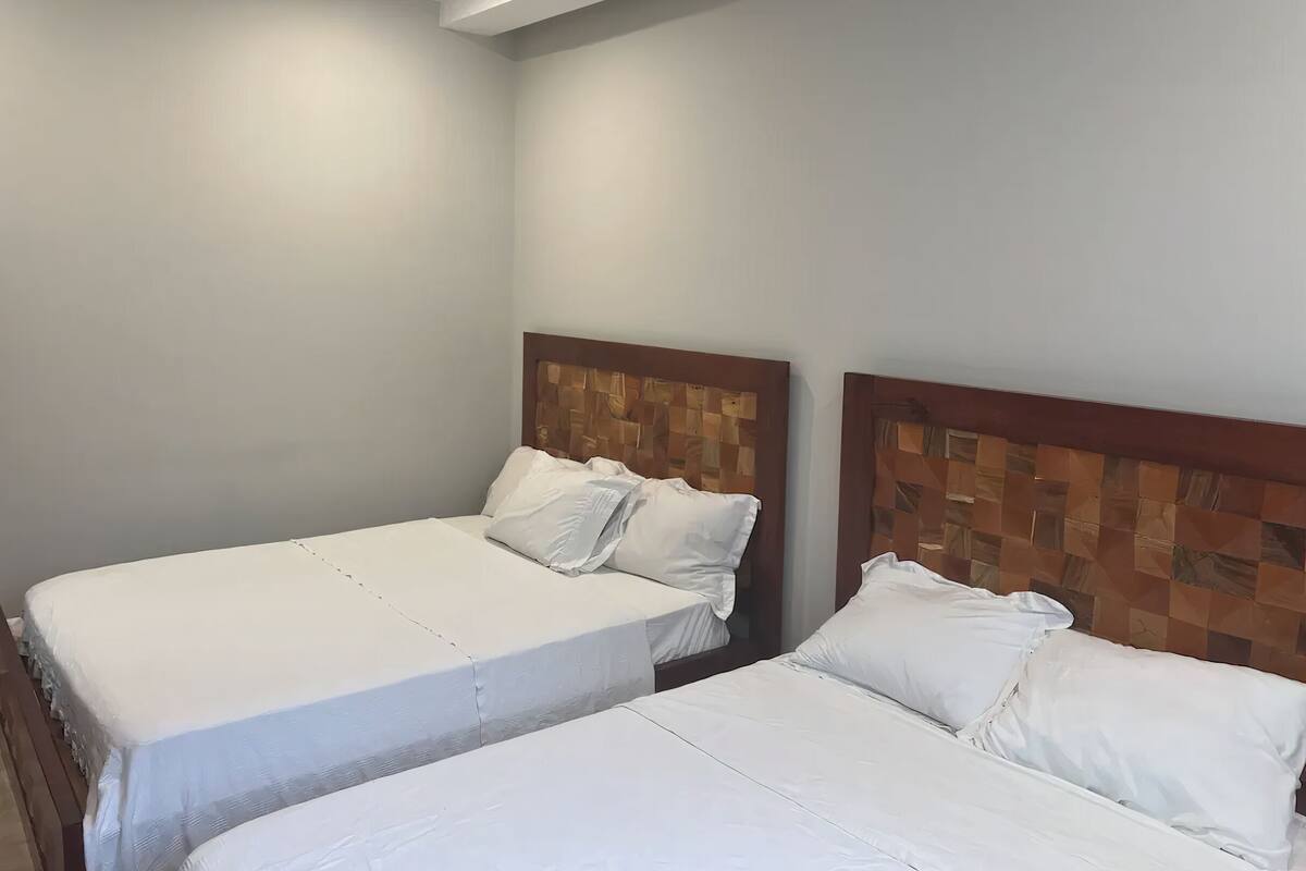 A hotel room with two single beds, each with white bedding and wooden headboards.