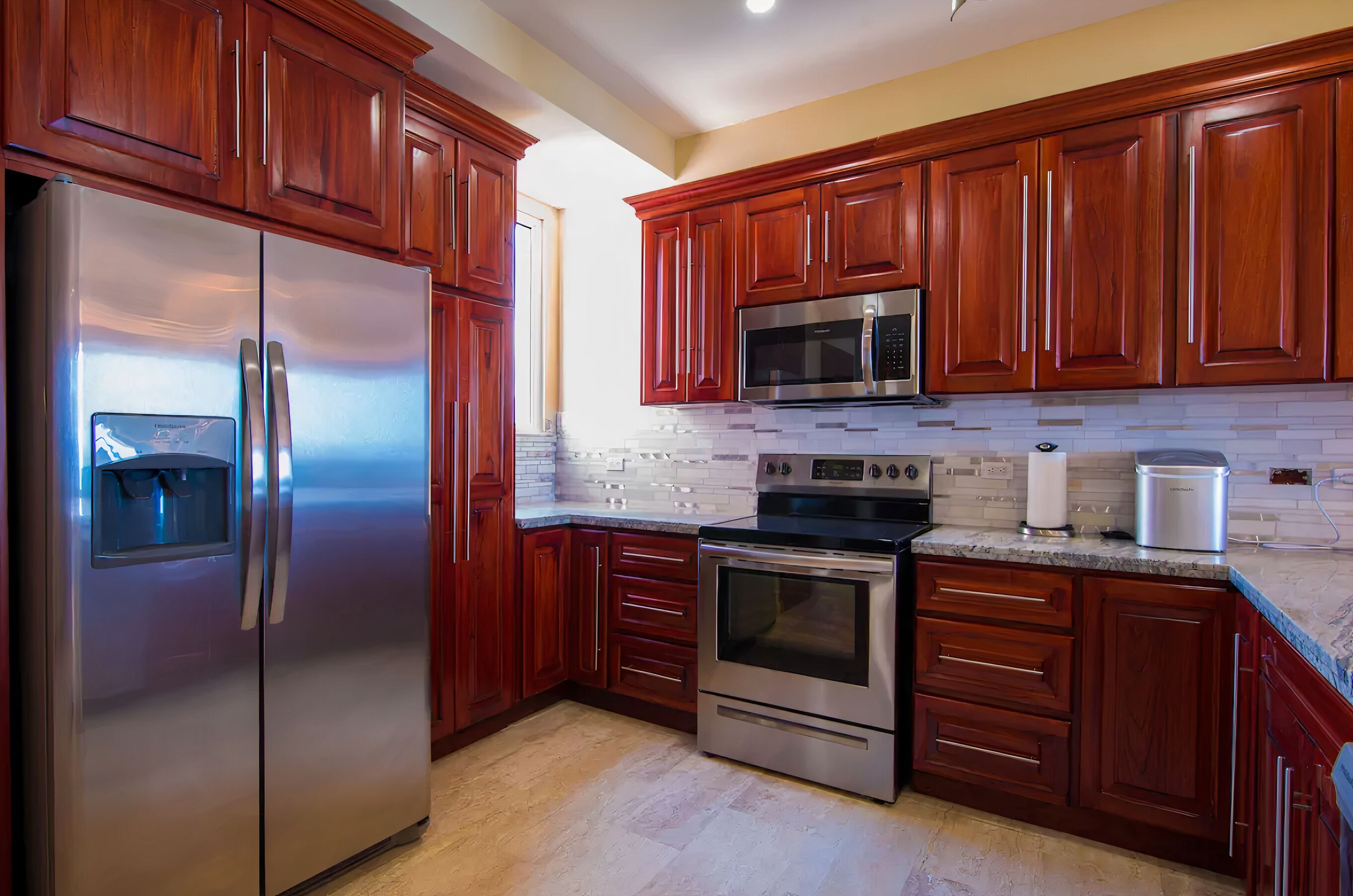 A kitchen with wooden cabinets, stainless steel appliances, and a tiled backsplash.