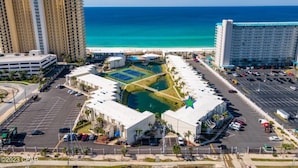 A hotel with a central courtyard, parking lot, and ocean view.