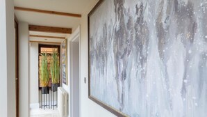 A hallway with a large abstract painting, a radiator, and tall plants. - Stable Lodge Boutique B&B (Cheltenham)