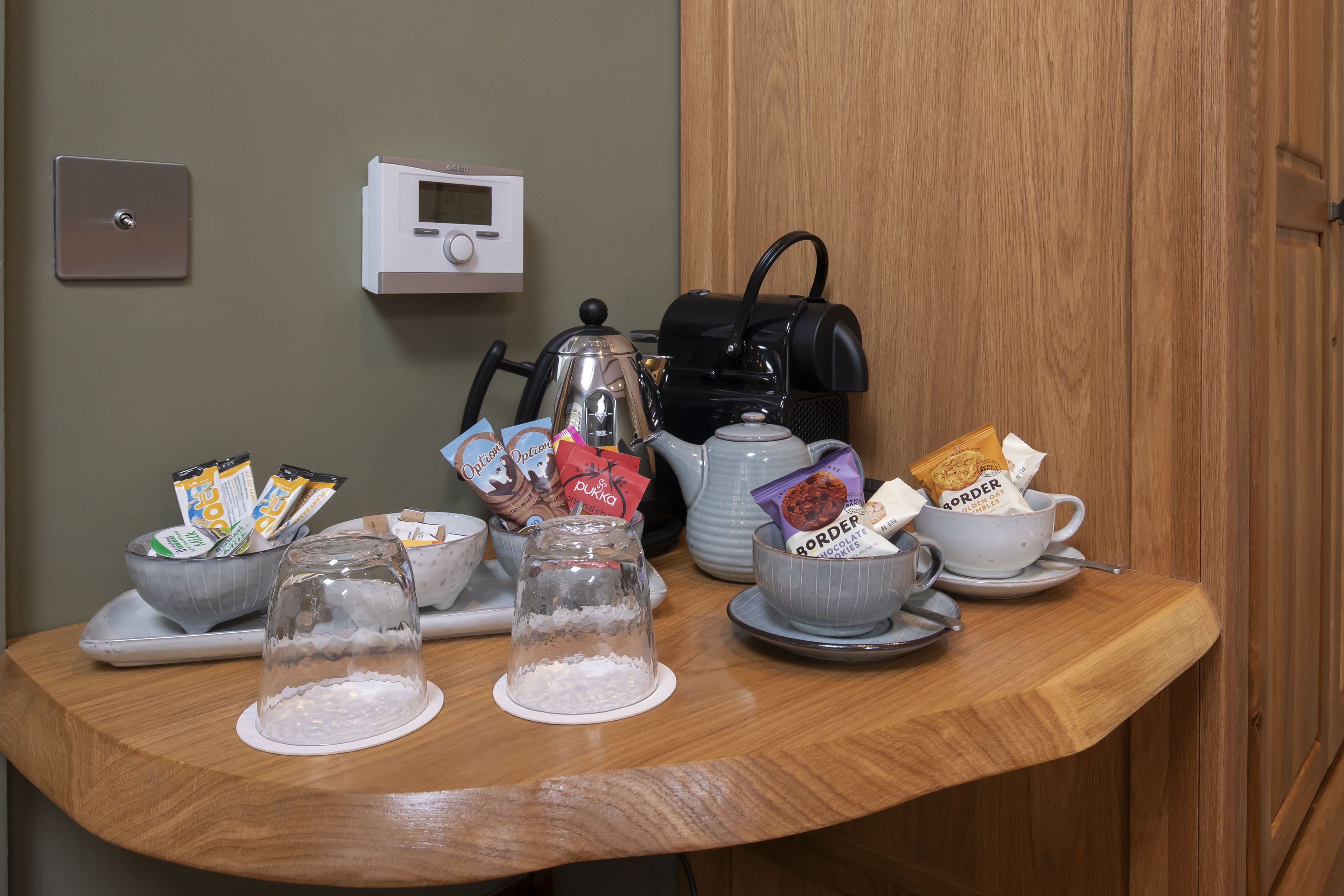 Ein Frühstückstisch mit Wasserkocher, Kaffeemaschine und verschiedenen Speisen.