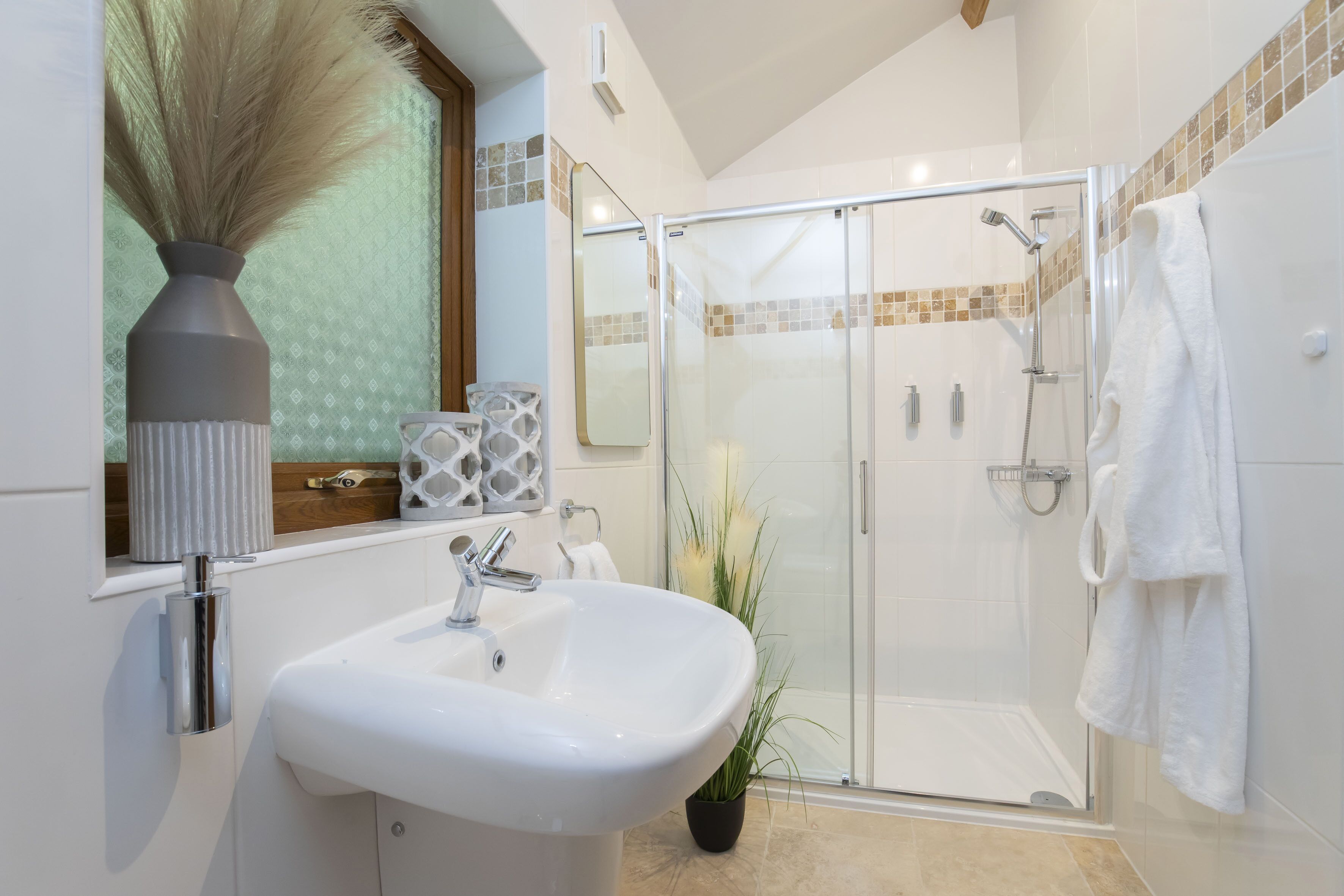 Un baño moderno con ducha vidriada, un lavabo blanco y un espejo.