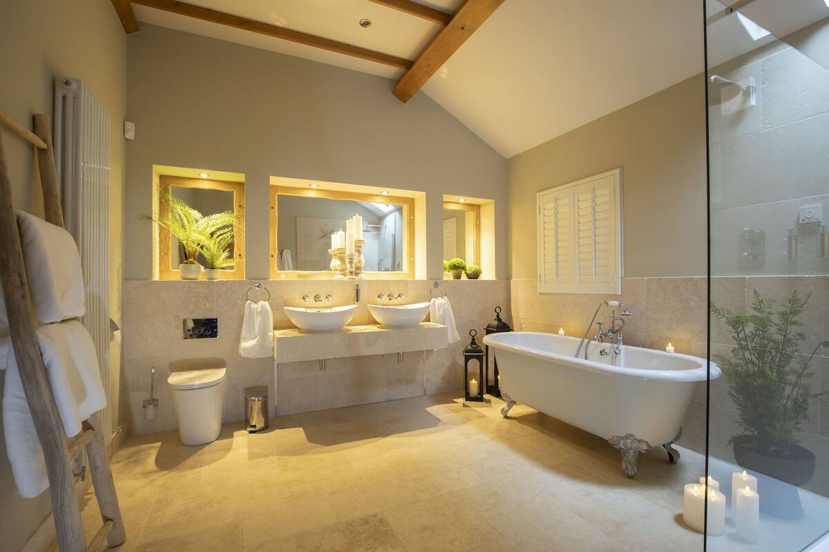 A bathroom with a freestanding bathtub, two sinks, a toilet, and a glass shower enclosure.