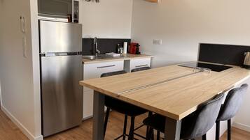 A compact kitchen with a built-in refrigerator, a coffee machine, and a small countertop.