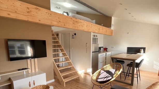 Un salon moderne avec un lit en mezzanine, un coin repas et une cuisine.