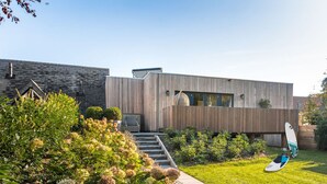 A modern house with a wooden facade, a visible staircase, and a garden with hydrangeas. - Luxury 6p. villa in Gaasterland near the woods and close to the (kite)beach. (Rijs)
