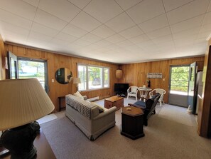 Una habitación acogedora con sofá, una mesita, televisor y ventana con vistas al exterior.