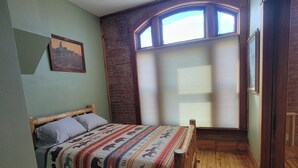 A bedroom with a wooden bed, a ceiling fan, a window with blinds, and a painting on the wall. - Experience history of brothel, 4 bedrooms, 6 min from attractions. Pets friendly (Custer)