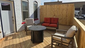 A wooden deck with a round table and four chairs, a red sofa, and a white door. - Experience history of brothel, 4 bedrooms, 6 min from attractions. Pets friendly (Custer)