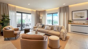 A modern living room with a sofa, armchairs, and a coffee table. There is a balcony with outdoor furniture visible through the windows. - Beautiful home in Kastelir with sauna (Kastelir)