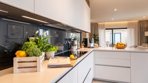 A modern kitchen with white cabinetry, a built-in oven, and a coffee machine. There is a fruit bowl on the counter and a plant on the windowsill. - Beautiful home in Kastelir with sauna (Kastelir)