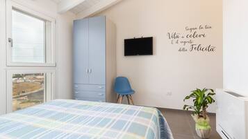 Un dormitorio con cama, armario, silla, televisor y una pared con una cita motivacional.