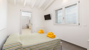 Habitación de hotel con una cama, un televisor montado en la pared y una ventana con vistas.