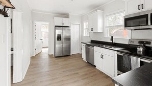 Une cuisine moderne avec des meubles blancs, des appareils en acier inoxydable et un plancher en bois.