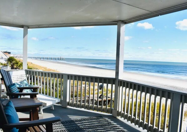 A covered outdoor area with a view of the beach and a pier in the distance. - Oceanfront retreat with Spectacular Views (Surfside Beach)