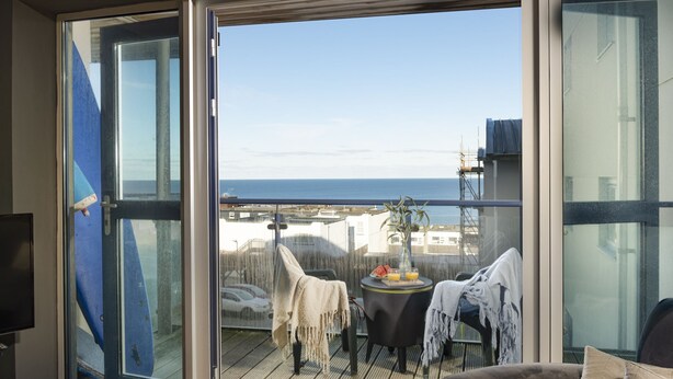 Ein Balkon mit Meerblick, ein Tisch mit Getränken und ein Stuhl.