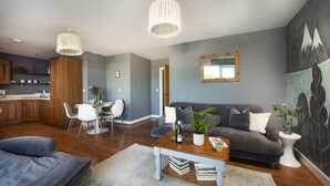 Ein modernes Wohnzimmer mit grauem Sofa, einem Couchtisch und einem Essbereich mit weißem Tisch und Stühlen.