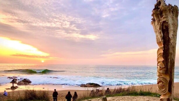 A beach with people walking along the shore, a wooden post with carvings, and the ocean with waves. - Maison au cœur de la Chaume + Garage fermé (Les Sables-d'Olonne)
