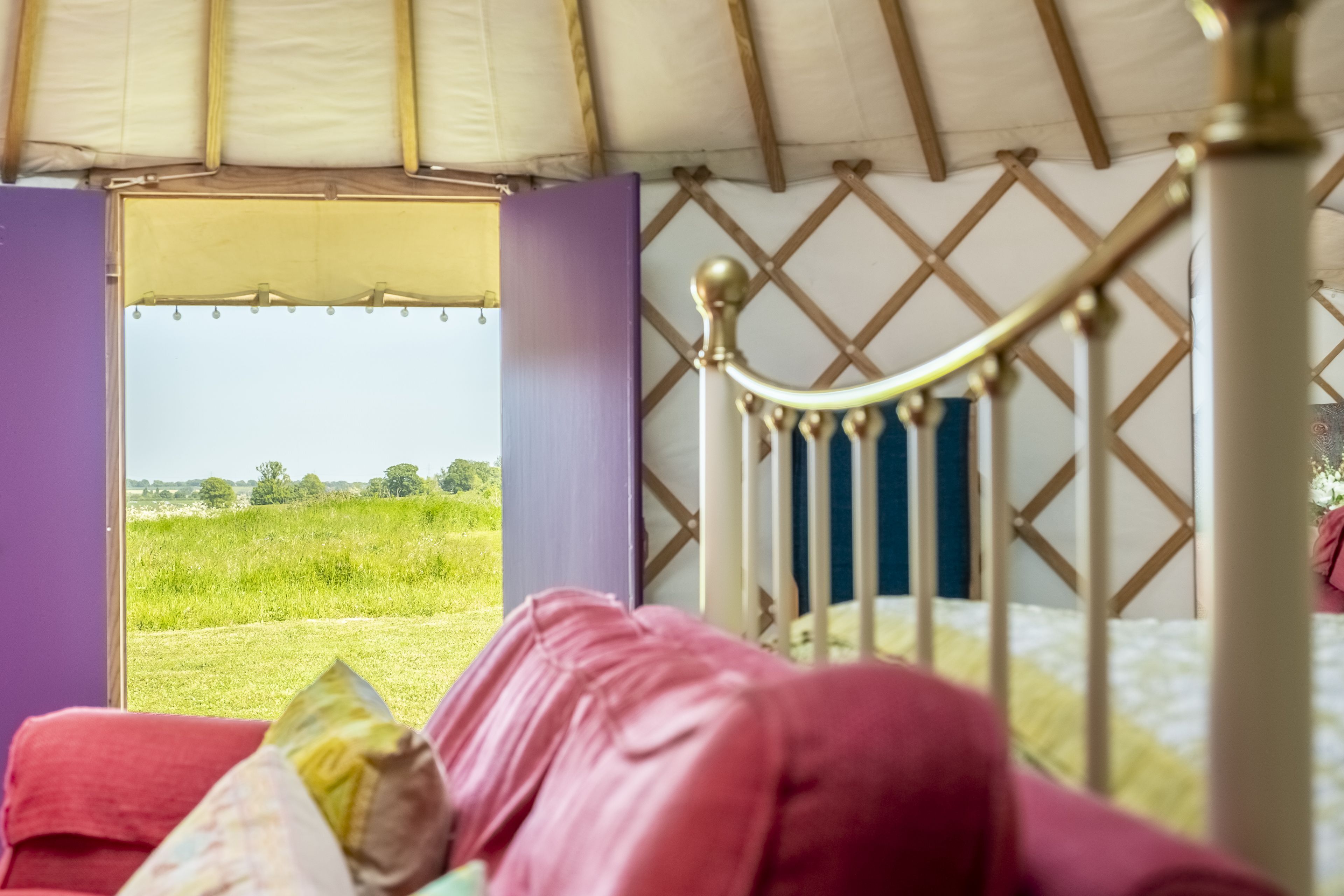 Een kamer met een bed en uitzicht op een grasveld, met een openslaande raamstructuur.