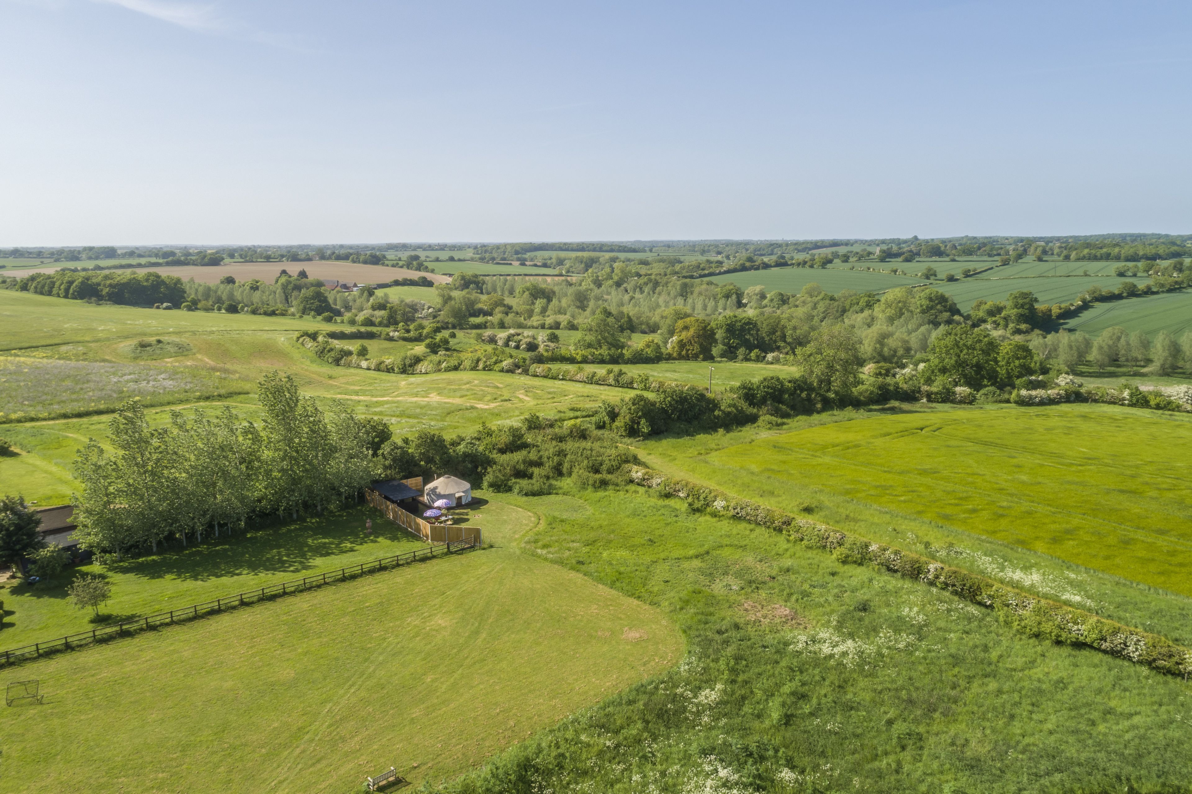 A rural landscape with fields, trees, and a small building.