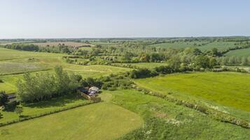 A rural landscape with fields, trees, and a small building.