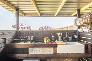 Outdoor kitchen area with sink, gas stove, and storage.